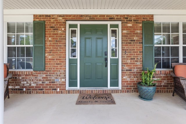 doorway to property featuring brick siding and a porch
