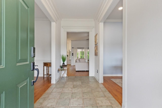 foyer entrance with crown molding, baseboards, and light wood-style floors