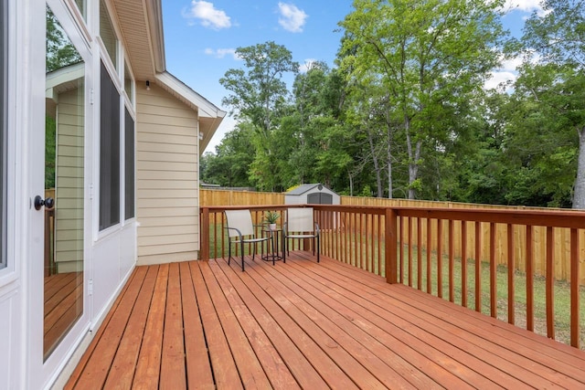 deck featuring an outdoor structure, a shed, and a fenced backyard