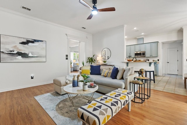living room featuring visible vents, crown molding, and ceiling fan