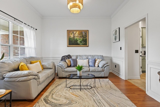 living area with crown molding, wainscoting, and wood finished floors