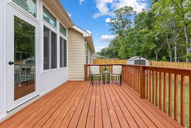 deck featuring an outdoor structure, a fenced backyard, a shed, and outdoor dining space
