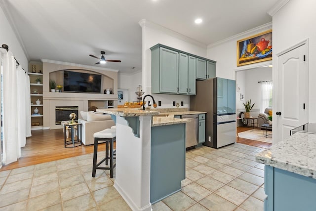 kitchen with ornamental molding, a sink, a peninsula, a ceiling fan, and appliances with stainless steel finishes