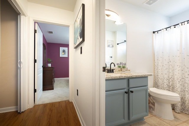 full bath with toilet, visible vents, wood finished floors, and vanity