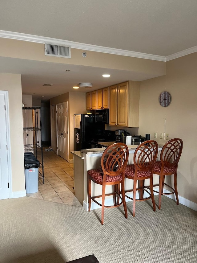 215 W College Ave Unit 511, Tallahassee, FL 32301 - kitchen with ornamental molding, a kitchen breakfast bar, black appliances, baseboards, and a peninsula