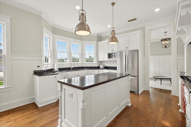 4640 Grove Park Dr, Tallahassee, FL 32311 - kitchen featuring stainless steel appliances, dark countertops, a decorative wall, dark wood-style floors, and a wainscoted wall