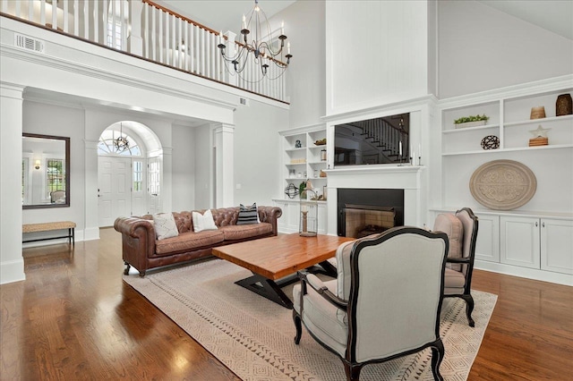 4640 Grove Park Dr, Tallahassee, FL 32311 - living room featuring a high ceiling, a chandelier, wood finished floors, a fireplace, and built in features