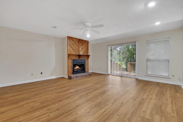 unfurnished living room featuring light wood-type flooring, ceiling fan, and a large fireplace