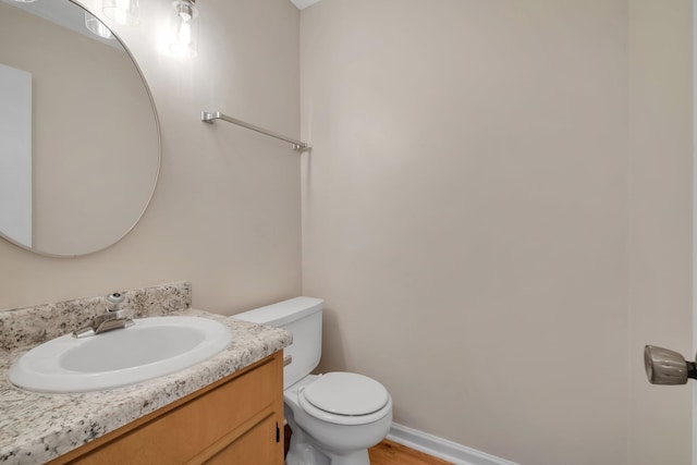 bathroom with toilet, vanity, and hardwood / wood-style flooring