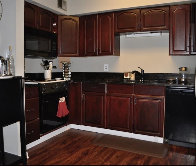 kitchen with dark wood-type flooring, dark stone counters, sink, and black appliances