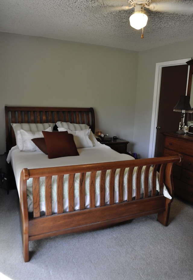 carpeted bedroom featuring ceiling fan and a textured ceiling