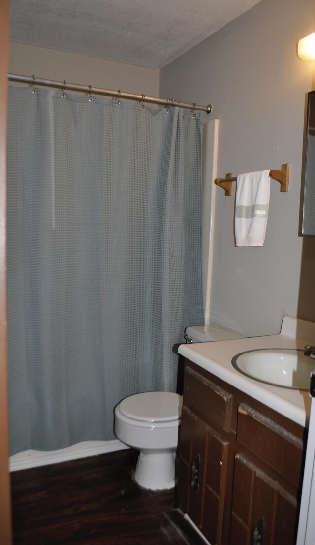 bathroom featuring hardwood / wood-style floors, vanity, a textured ceiling, curtained shower, and toilet