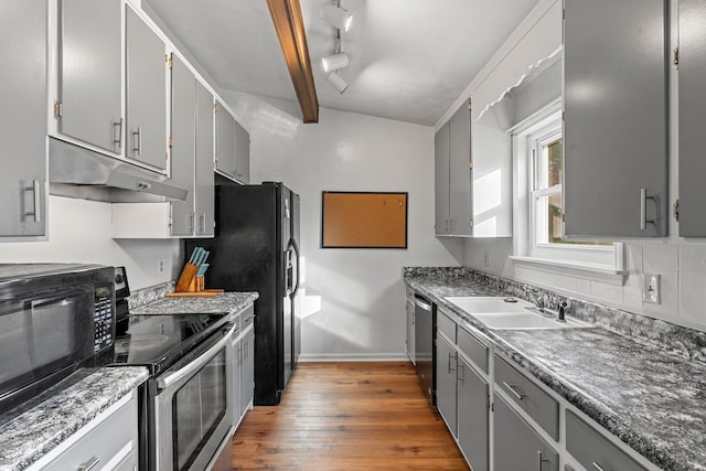 kitchen featuring gray cabinets, appliances with stainless steel finishes, hardwood / wood-style floors, beamed ceiling, and sink