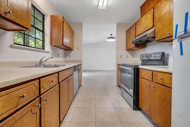 kitchen with appliances with stainless steel finishes, brown cabinets, a sink, light countertops, and under cabinet range hood