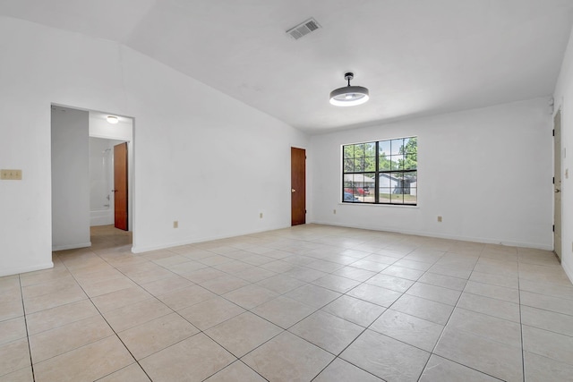 spare room featuring visible vents, light tile patterned floors, and vaulted ceiling