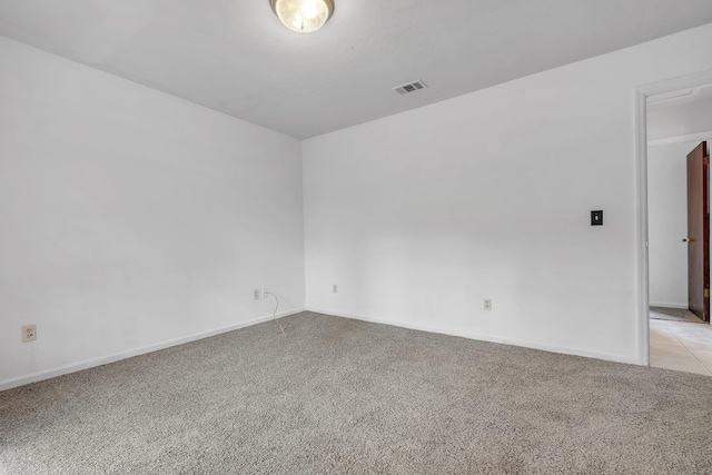 empty room with baseboards, visible vents, and light carpet
