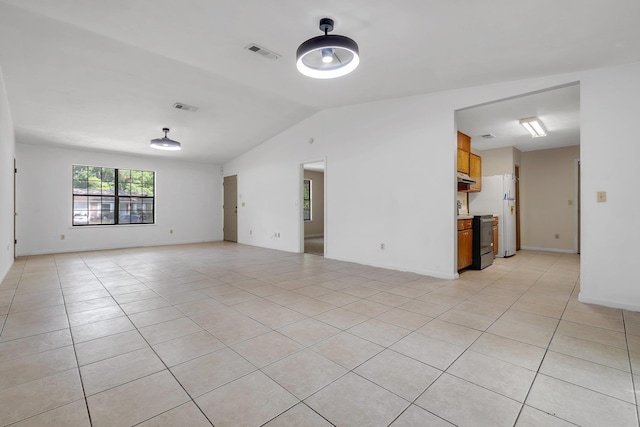 spare room featuring baseboards, visible vents, light tile patterned floors, and vaulted ceiling