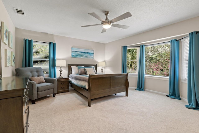 bedroom featuring a textured ceiling, multiple windows, light colored carpet, and visible vents