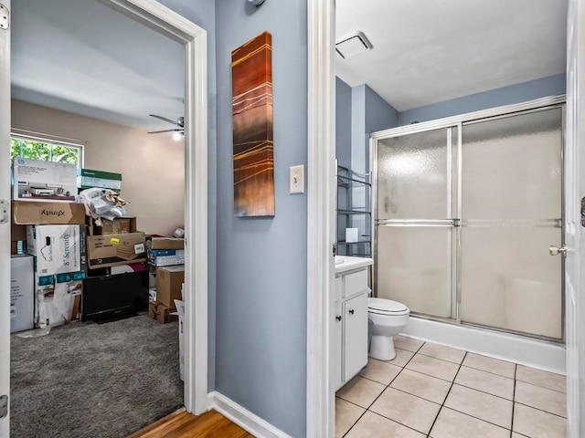 bathroom featuring a shower with door, tile patterned flooring, ceiling fan, vanity, and toilet