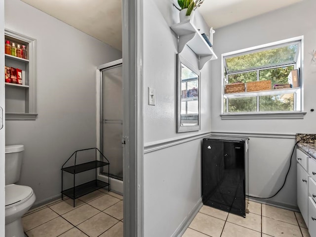 bathroom with a shower with shower door, vanity, toilet, and tile patterned flooring