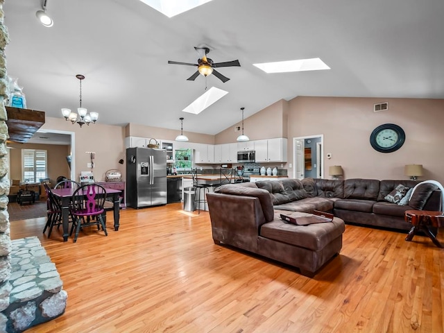 living room featuring ceiling fan with notable chandelier, light hardwood / wood-style flooring, and high vaulted ceiling