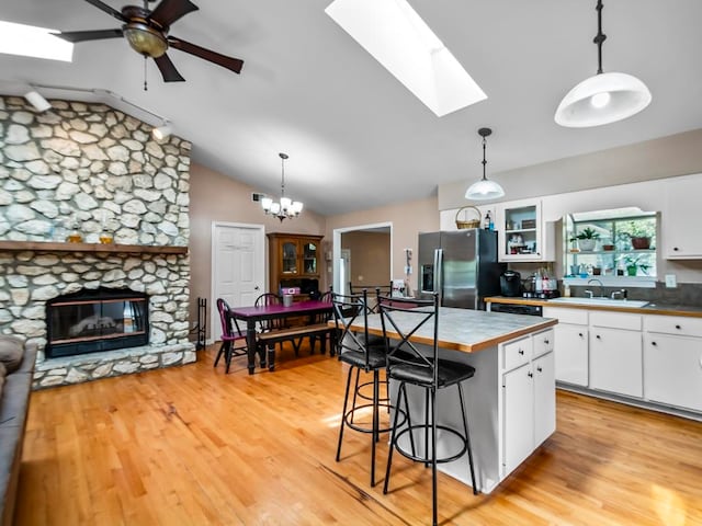 kitchen featuring lofted ceiling with skylight, a kitchen island, white cabinetry, and stainless steel fridge