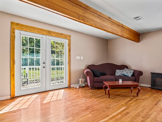 interior space with beam ceiling, french doors, and light hardwood / wood-style flooring