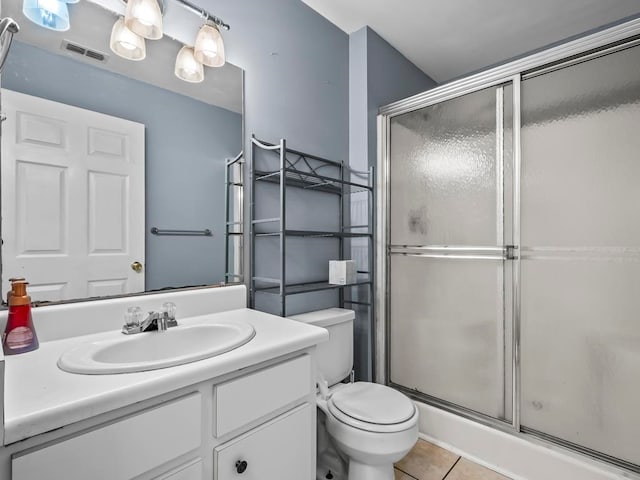 bathroom featuring vanity, a shower with shower door, tile patterned floors, and toilet