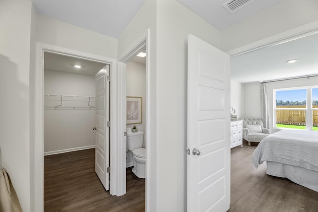 bedroom with a spacious closet, a closet, connected bathroom, and dark hardwood / wood-style floors