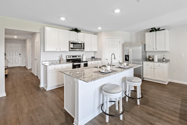 kitchen featuring sink, appliances with stainless steel finishes, an island with sink, a kitchen breakfast bar, and white cabinets