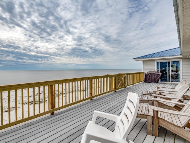 wooden deck featuring a water view, a grill, and a beach view