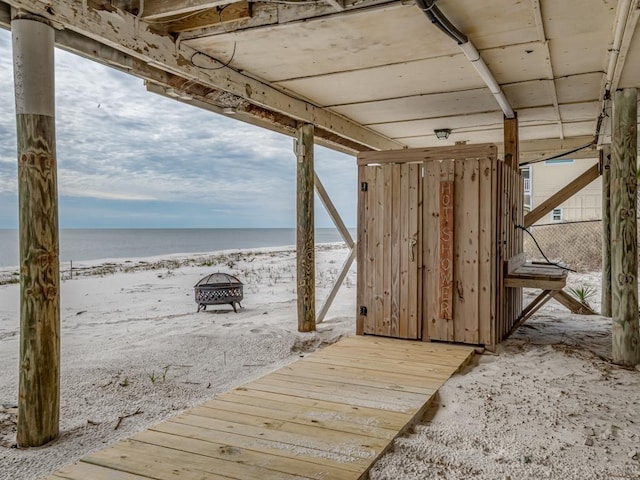 dock area featuring a water view, a beach view, and an outdoor fire pit