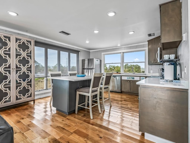 kitchen featuring a kitchen island, light hardwood / wood-style floors, a healthy amount of sunlight, and appliances with stainless steel finishes