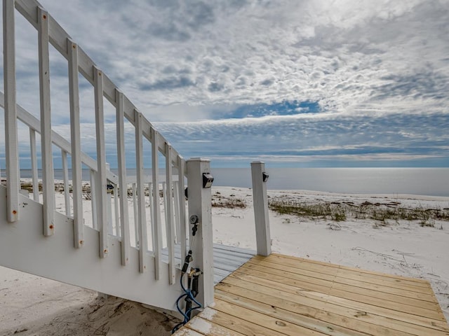 view of dock featuring a water view and a beach view