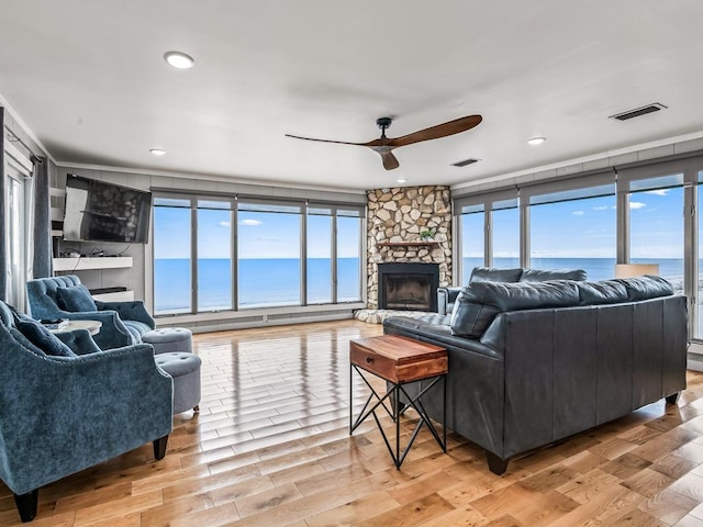 living room with light hardwood / wood-style flooring, a fireplace, ceiling fan, and plenty of natural light