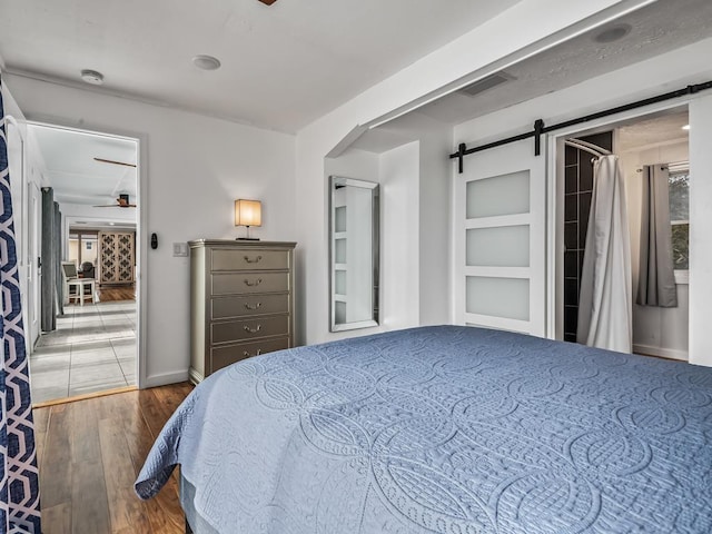 bedroom with a barn door and dark hardwood / wood-style floors