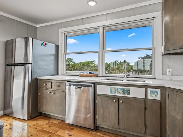 kitchen with dark brown cabinetry, stainless steel appliances, sink, and light wood-type flooring