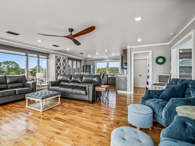 living room with ceiling fan, ornamental molding, and light hardwood / wood-style flooring