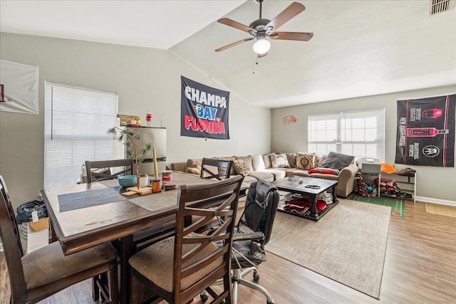 dining area featuring light wood finished floors, lofted ceiling, visible vents, ceiling fan, and baseboards