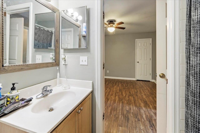 bathroom with baseboards, a ceiling fan, wood finished floors, and vanity