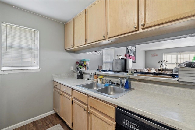 kitchen with light countertops, light brown cabinetry, open floor plan, a sink, and dishwasher