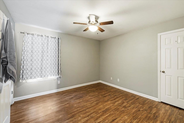 spare room with dark wood finished floors, baseboards, and ceiling fan