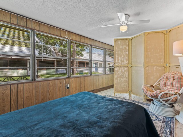 6 Parker Ave Unit 3 & 4, Lanark Village, FL 32323 - bedroom featuring light tile patterned floors, wood walls, a textured ceiling, and a ceiling fan