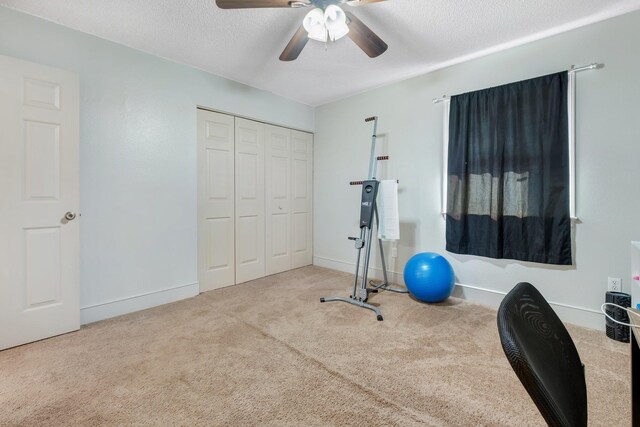 exercise area featuring light carpet, a textured ceiling, and ceiling fan