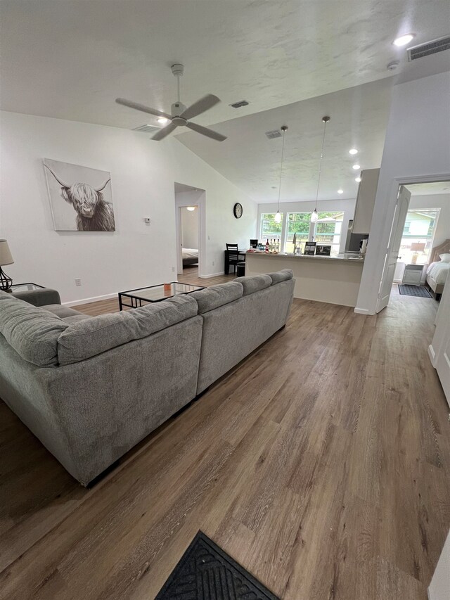 living room featuring hardwood / wood-style floors, ceiling fan, and vaulted ceiling