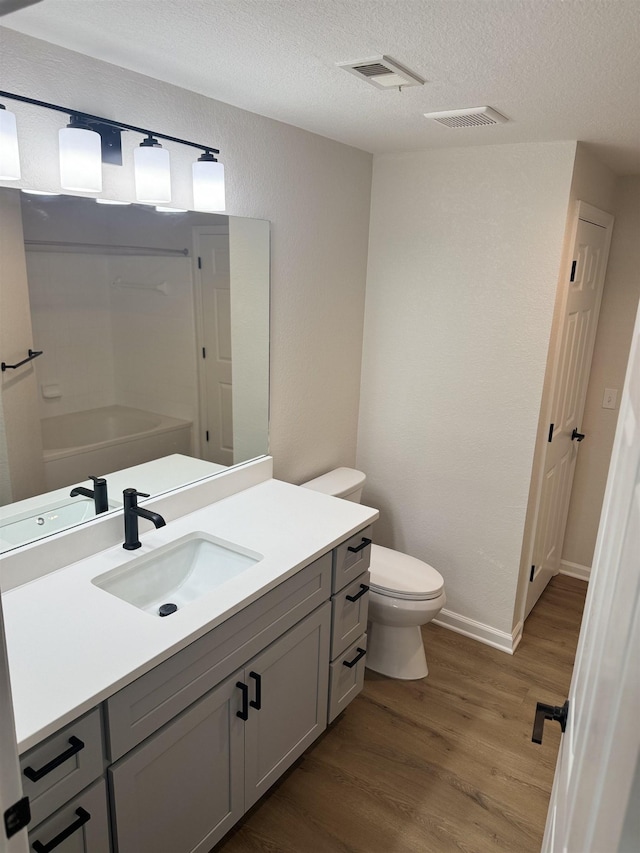 bathroom featuring vanity, hardwood / wood-style flooring, a textured ceiling, and toilet