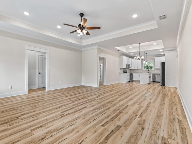117 Anhinga Trl, Carrabelle, FL 32322 - unfurnished living room featuring a tray ceiling, ceiling fan, a chandelier, light wood-type flooring, and crown molding