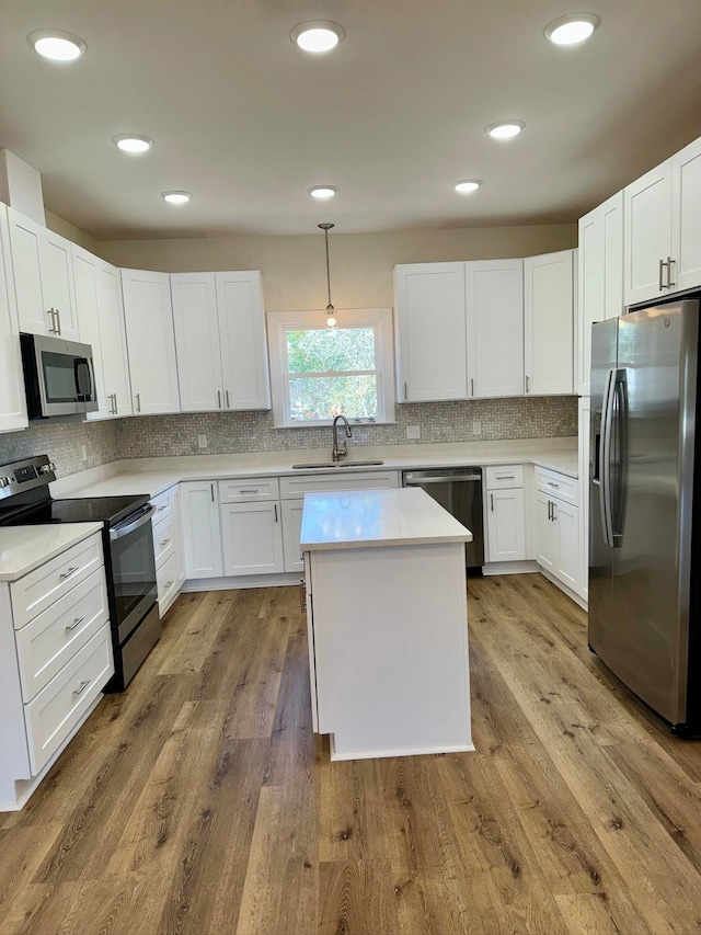 kitchen with white cabinetry, pendant lighting, hardwood / wood-style flooring, and appliances with stainless steel finishes