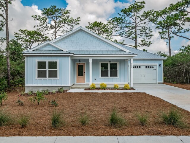 117 Anhinga Trl, Carrabelle, FL 32322 - view of front of property featuring board and batten siding, covered porch, an attached garage, concrete driveway, and a metal roof