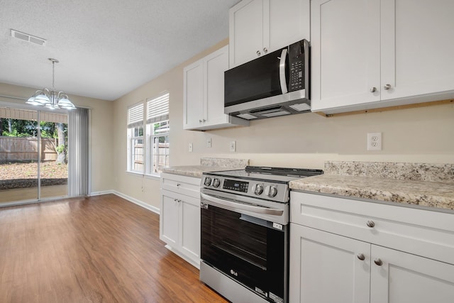 1790 Newman Ln, Tallahassee, FL 32312 - kitchen featuring appliances with stainless steel finishes, light wood-style floors, a chandelier, white cabinetry, and a textured ceiling